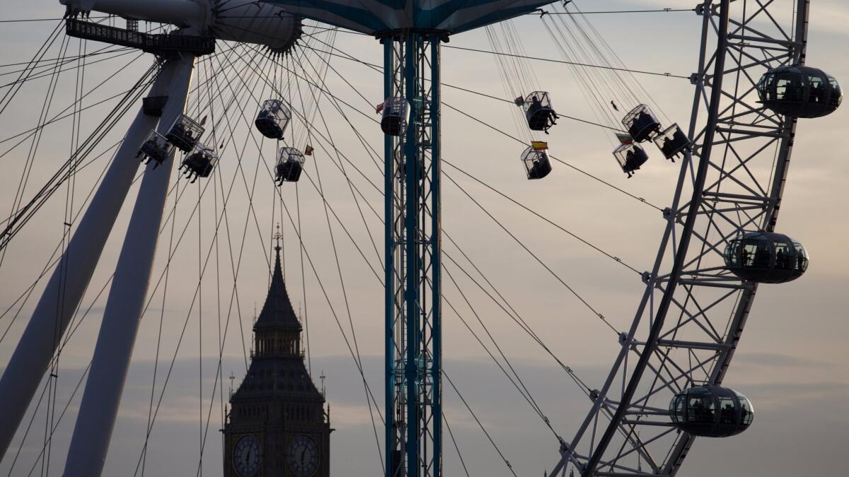 People ride on a fairground ride with the London Eye and Big Ben as a backdrop as the sun sets in London in September 2013.