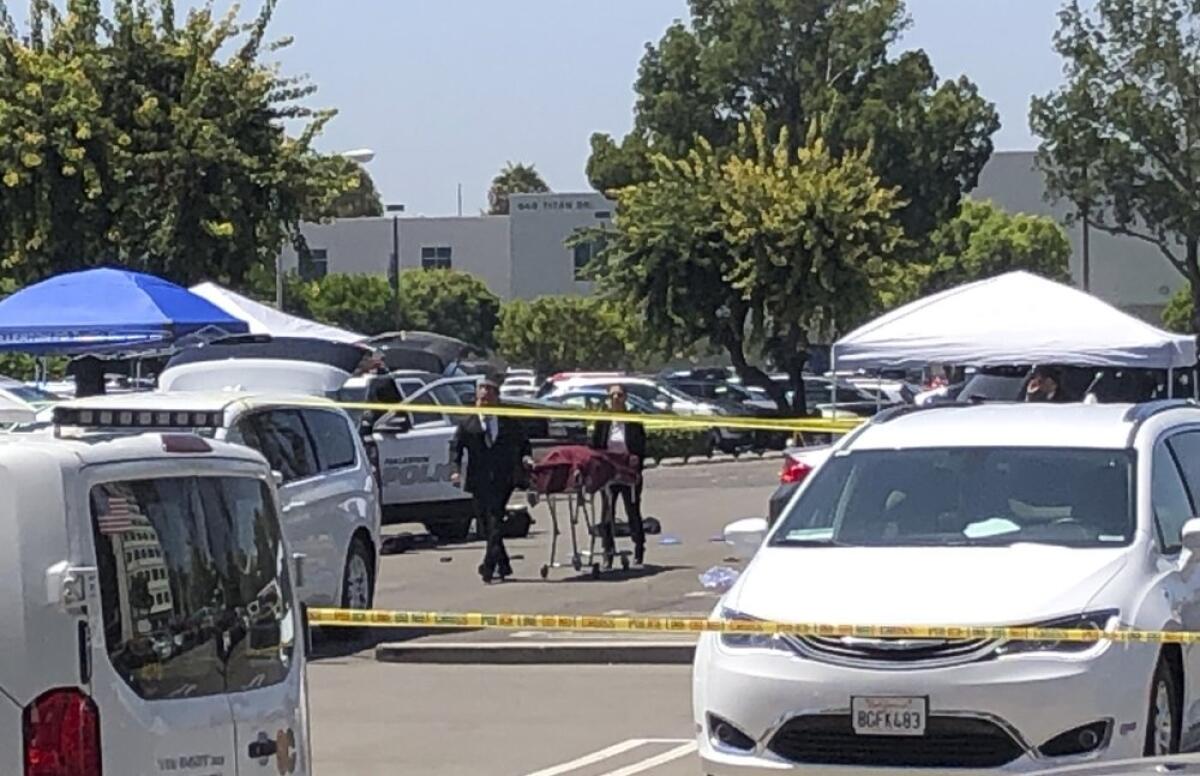 Orange County coroners remove a body  from a parking lot at California State University, Fullerton on Monday, Aug. 19, 2019. 