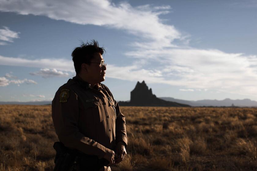 Officer Lojann Dennison photographed with a view of Shiprock in the background in New Mexico. She patrols one of seven districts on a Navajo reservation that is home to 180,000 people. Among 500 sovereign tribal nations in the U.S., the Navajo are among only a few with their own police force. The vast majority of the department is Native American.