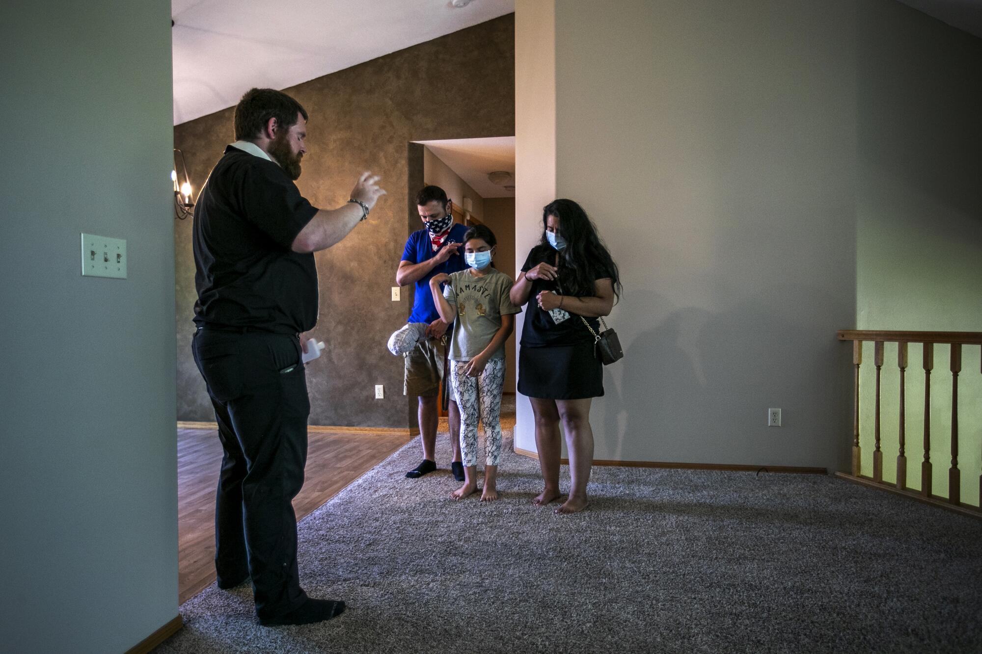 The Rev. Kristopher Cowles prays with the Centeno family, Abby, Abe and Astrid, inside their newly purchased home.