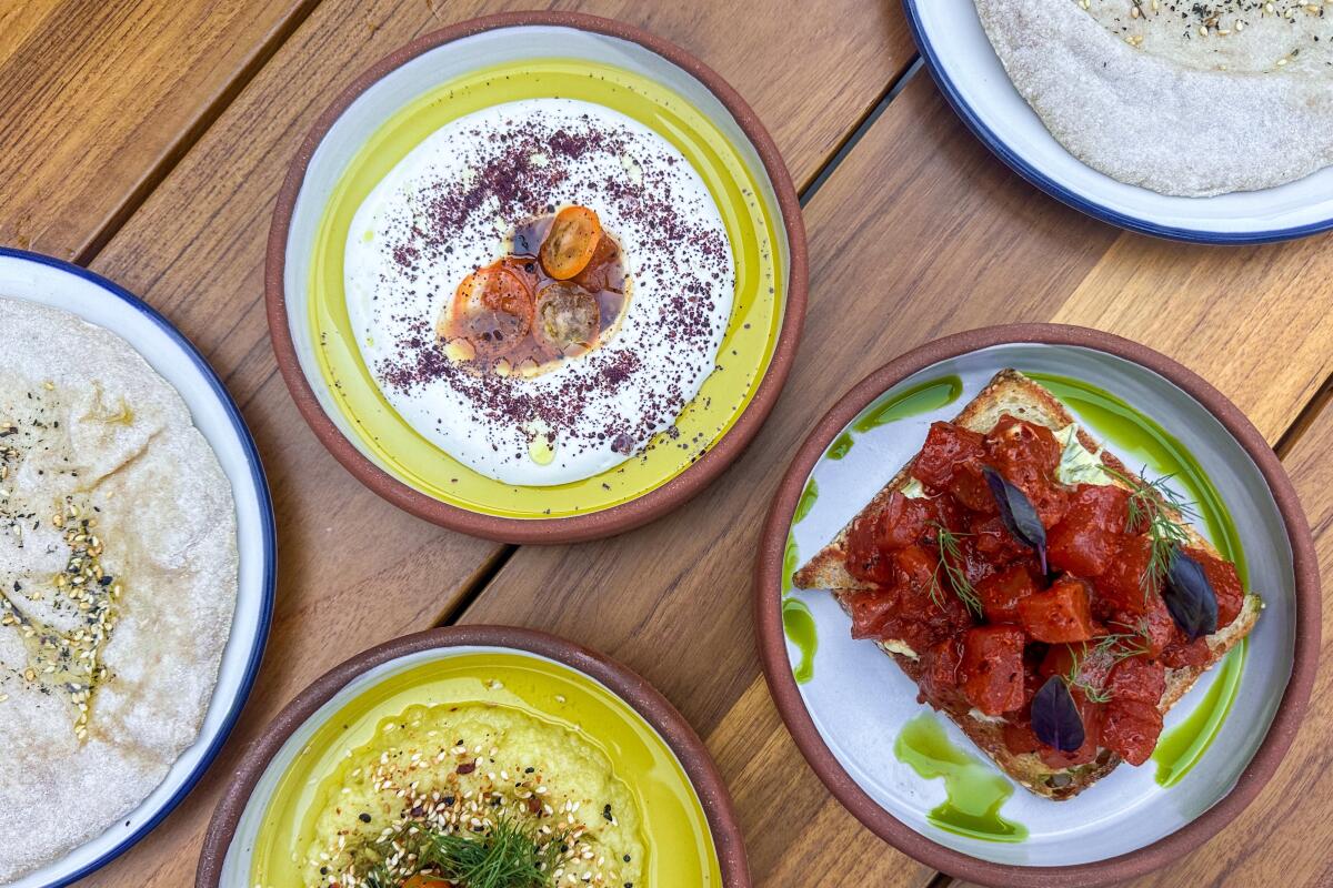 A spread of small plates on a wood-plank table at Cellar Hand in San Diego