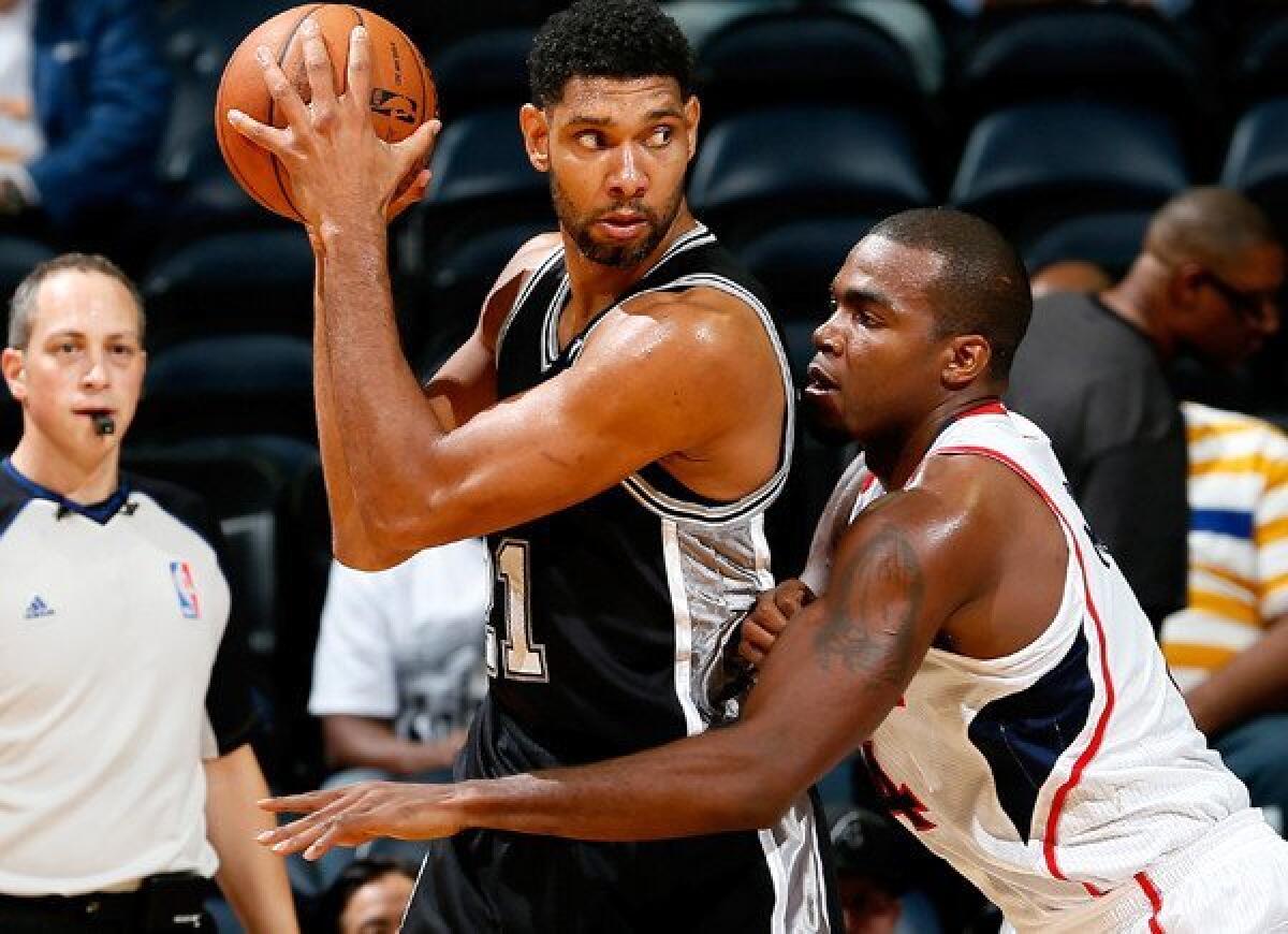 Spurs power forward Tim Duncan works in the post against Hawks power forward Paul Millsap during a preseason game.