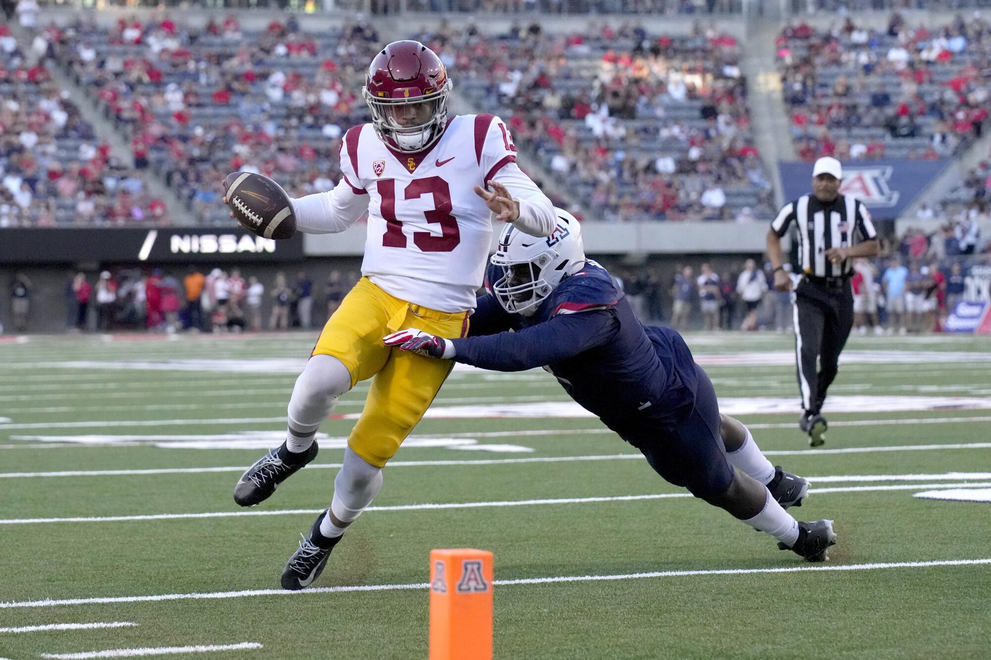 USC quarterback Caleb Williams tries to avoid Arizona defensive lineman Jalen Harris.