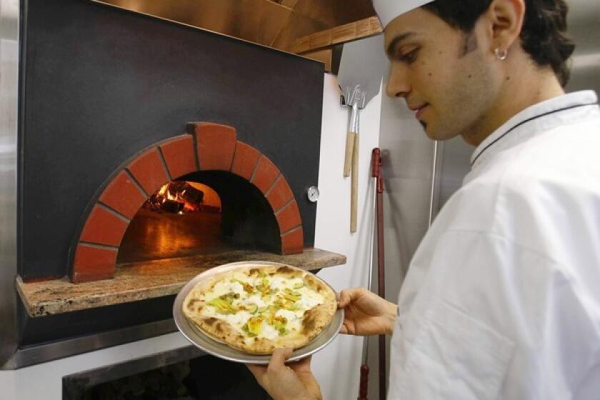 Pizzeria Il Fico chef Giuseppe Gentile takes a La Bianca pizza out of the oven.