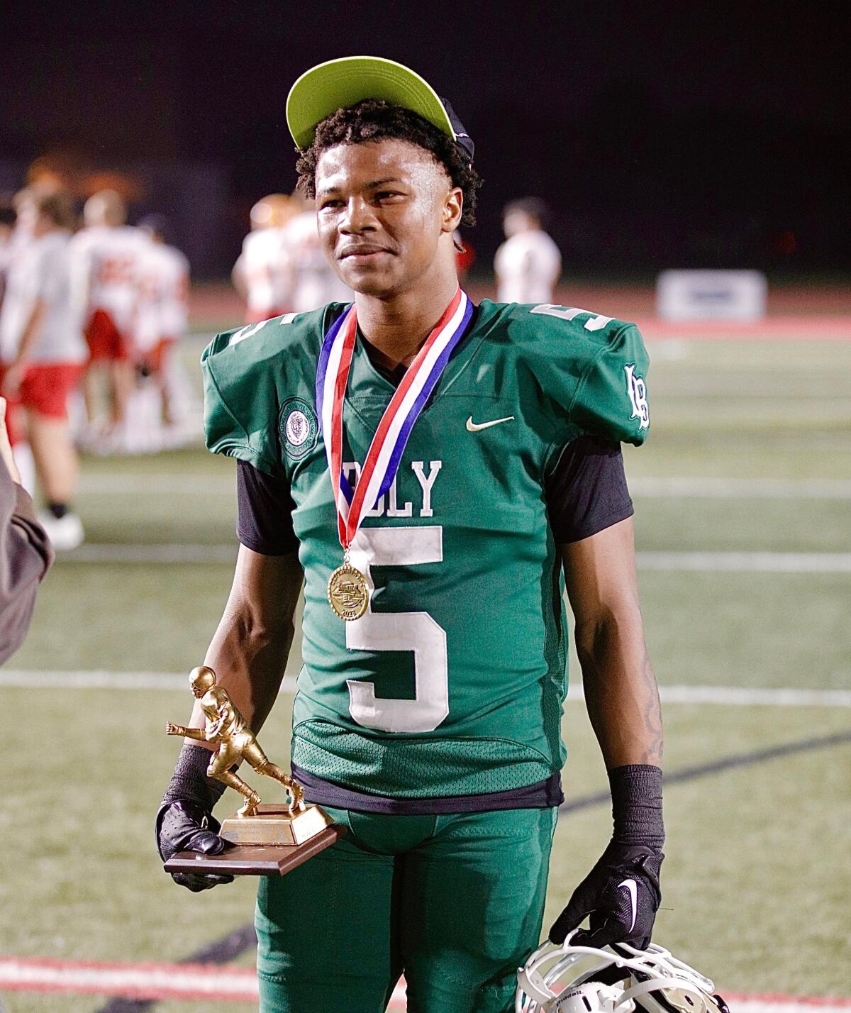 Long Beach Poly receiver Kamarie Smith holds his game MVP trophy after catching three touchdown passes in a win Friday.