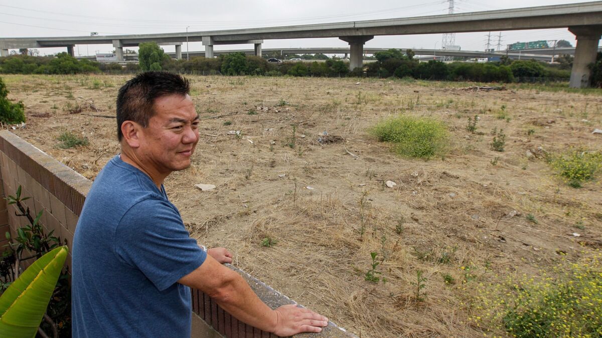 Harbor Gateway resident Craig Kusunoki looks at the site of a proposed 15-unit housing development next to the interchange of the 110 and freeways. Kusunoki and his neighbors say it would put housing too close to the interchange and a nearby freeway ramp.