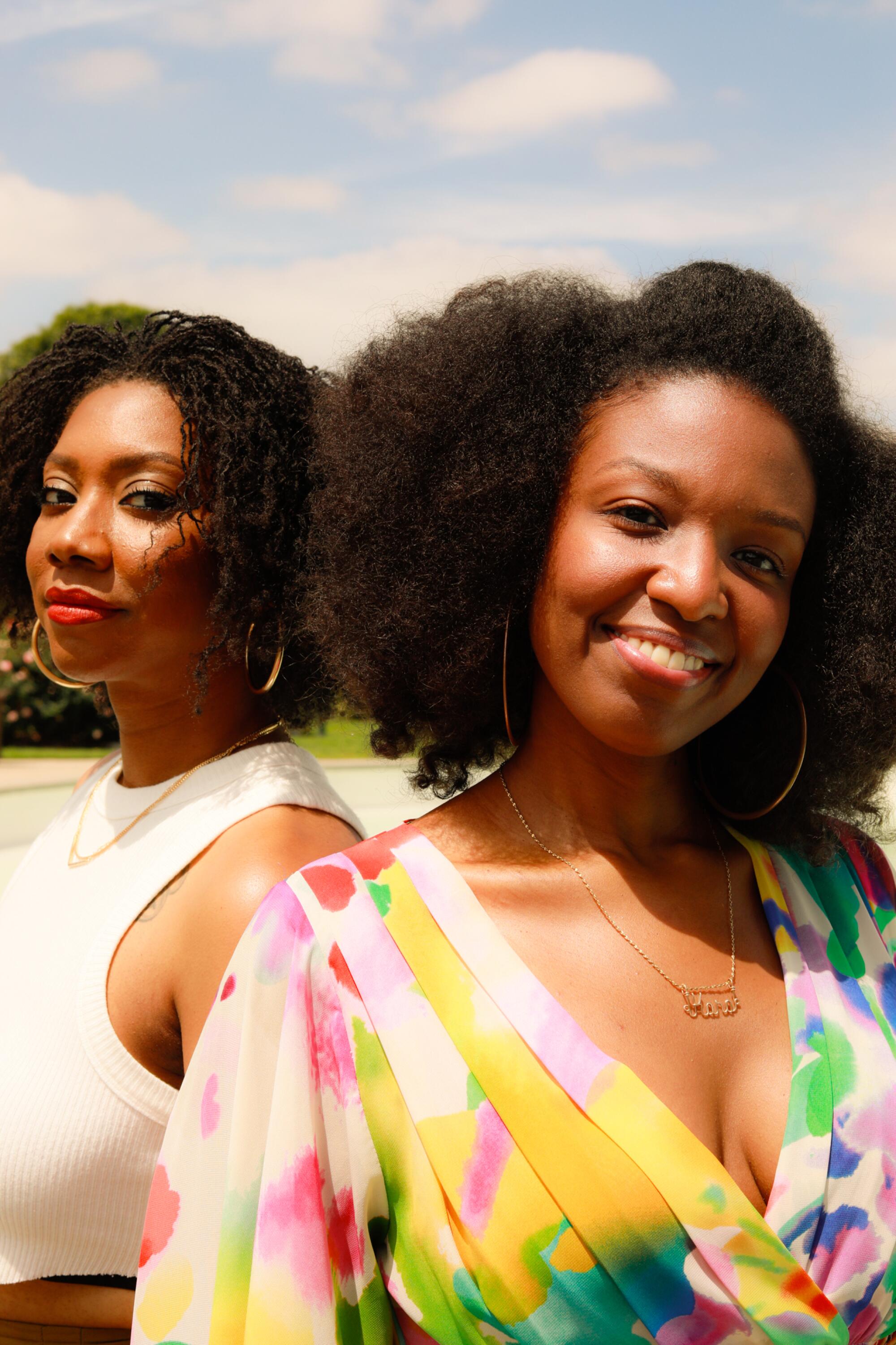 Two women pose for a photographer.