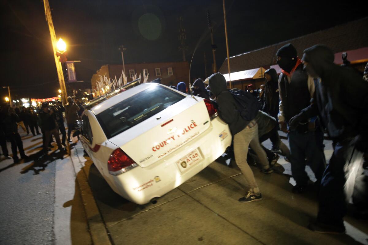 Protesters in Ferguson, Mo., shove a police car after the announcement of the grand jury decision not to indict police Officer Darren Wilson in the fatal shooting of Michael Brown, an unarmed black 18-year-old.