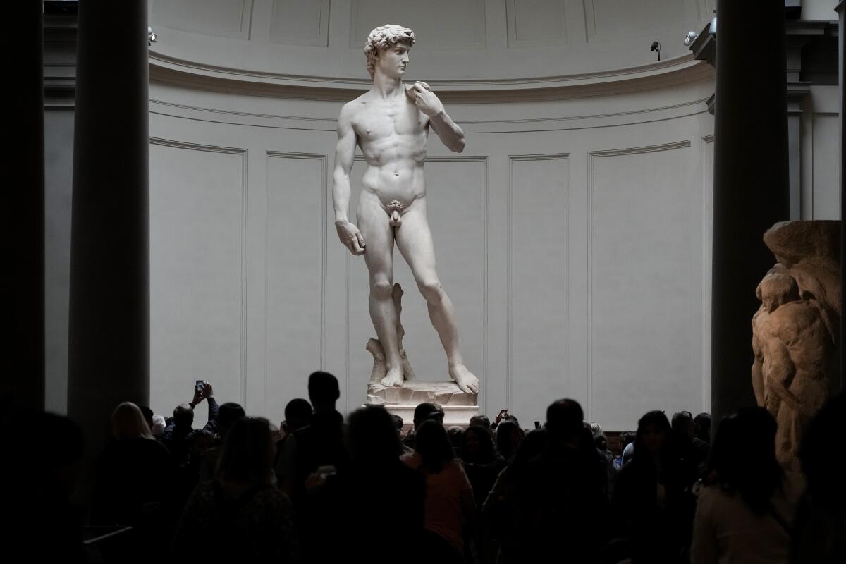 Michelangelo's "David" statue towering over a crowd of visitors