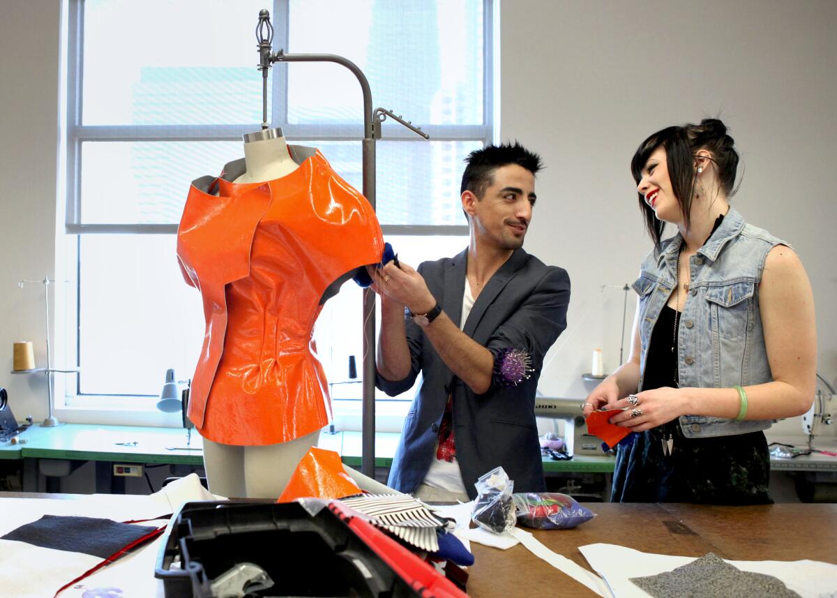 Fashion students Alejandro Ortega, left, and Jessica Dunn next to a sewing mannequin