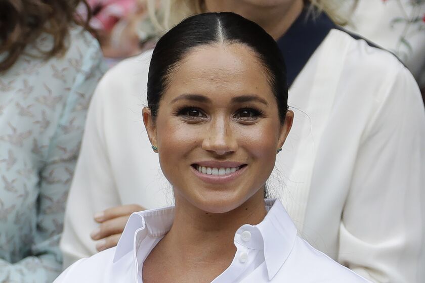 A smiling woman wearing a white blouse who has her hair pulled back