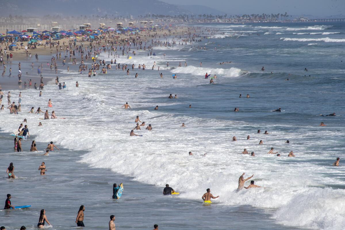 Beach goers take to the water to cool off amid high temperatures in Huntington Beach.
