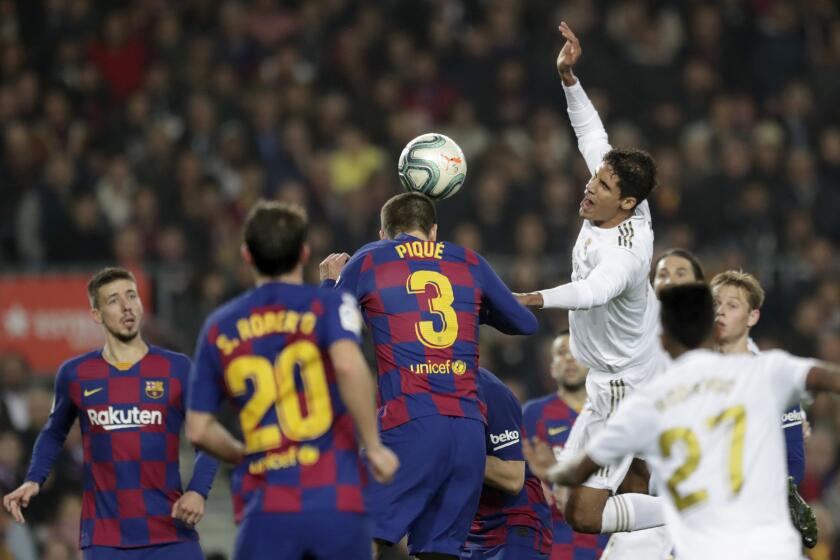 Real Madrid's Raphael Varane, top right, jumps for the ball with Barcelona's Gerard Pique, center, during a Spanish La Liga soccer match between Barcelona and Real Madrid at Camp Nou stadium in Barcelona, Spain, Wednesday, Dec. 18, 2019. Thousands of Catalan separatists are planning to protest around and inside Barcelona's Camp Nou Stadium during Wednesday's "Clasico". (AP Photo/Bernat Armangue)