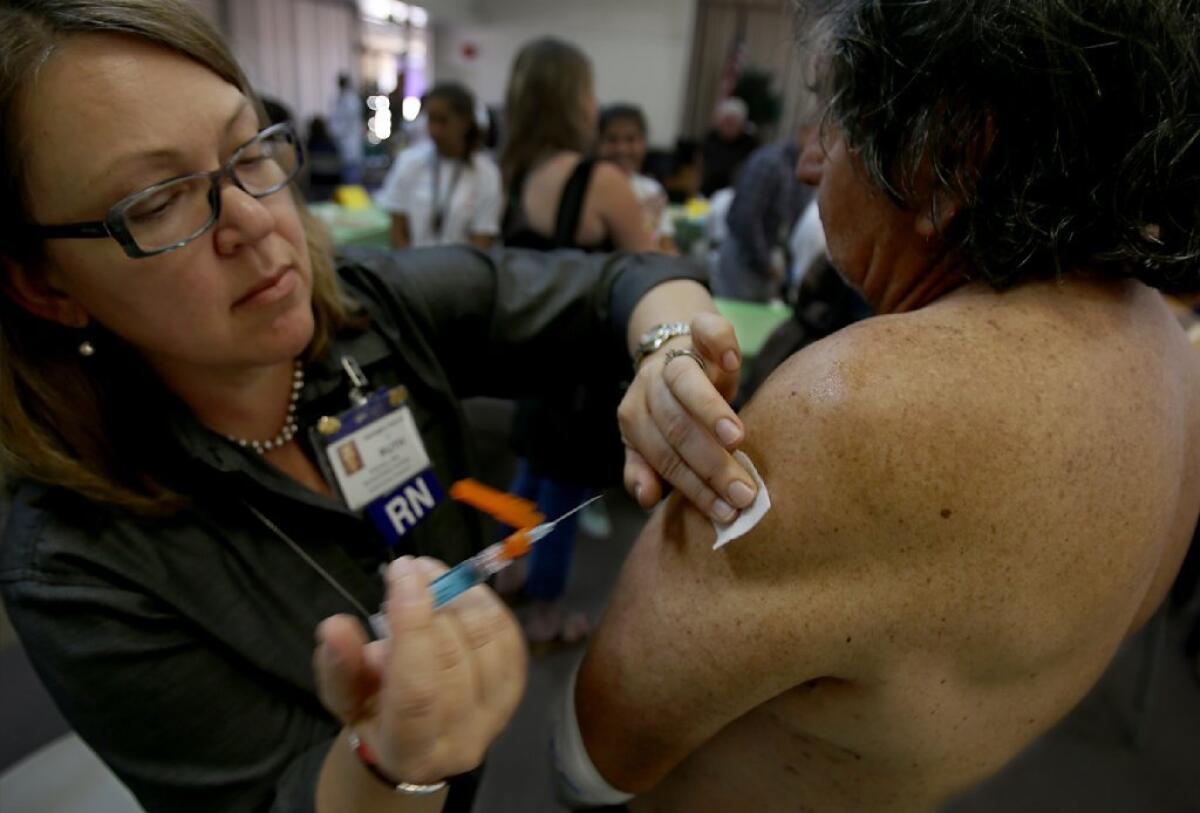 Nurse Ruth Pichaj administers a flu shot to Julio Hernandez on Tuesday. As the first flu death of the season was confirmed, L.A. County health officials urged everyone to get their flu vaccines.