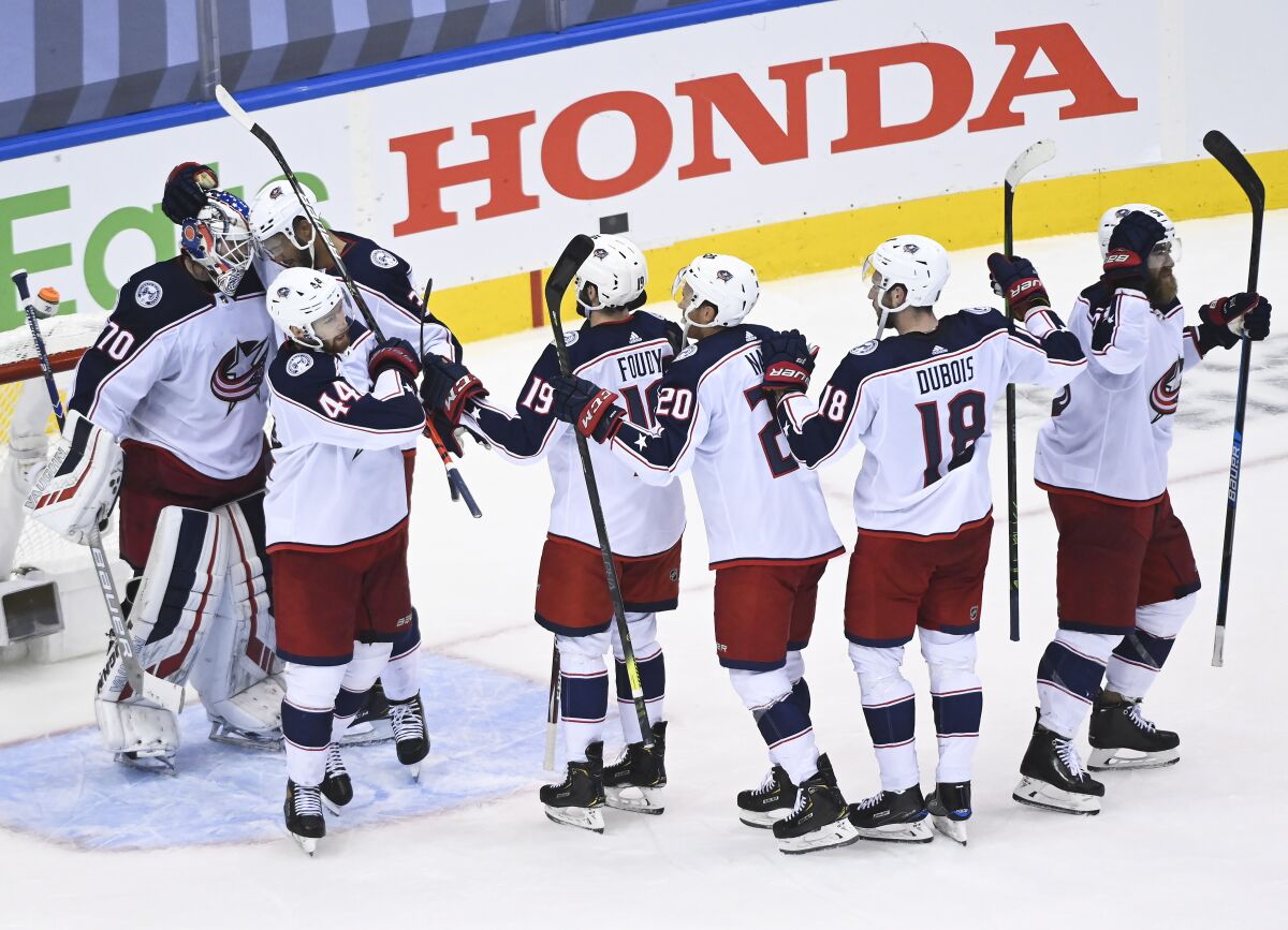 Columbus Blue Jackets goaltender Joonas Korpisalo (70) and teammates celebrate after defeating the Toronto Maple Leafs in an NHL hockey playoff game Sunday, Aug. 9, 2020, in Toronto. The Maple Leafs were eliminated from the playoffs. (Nathan Denette/The Canadian Press via AP)