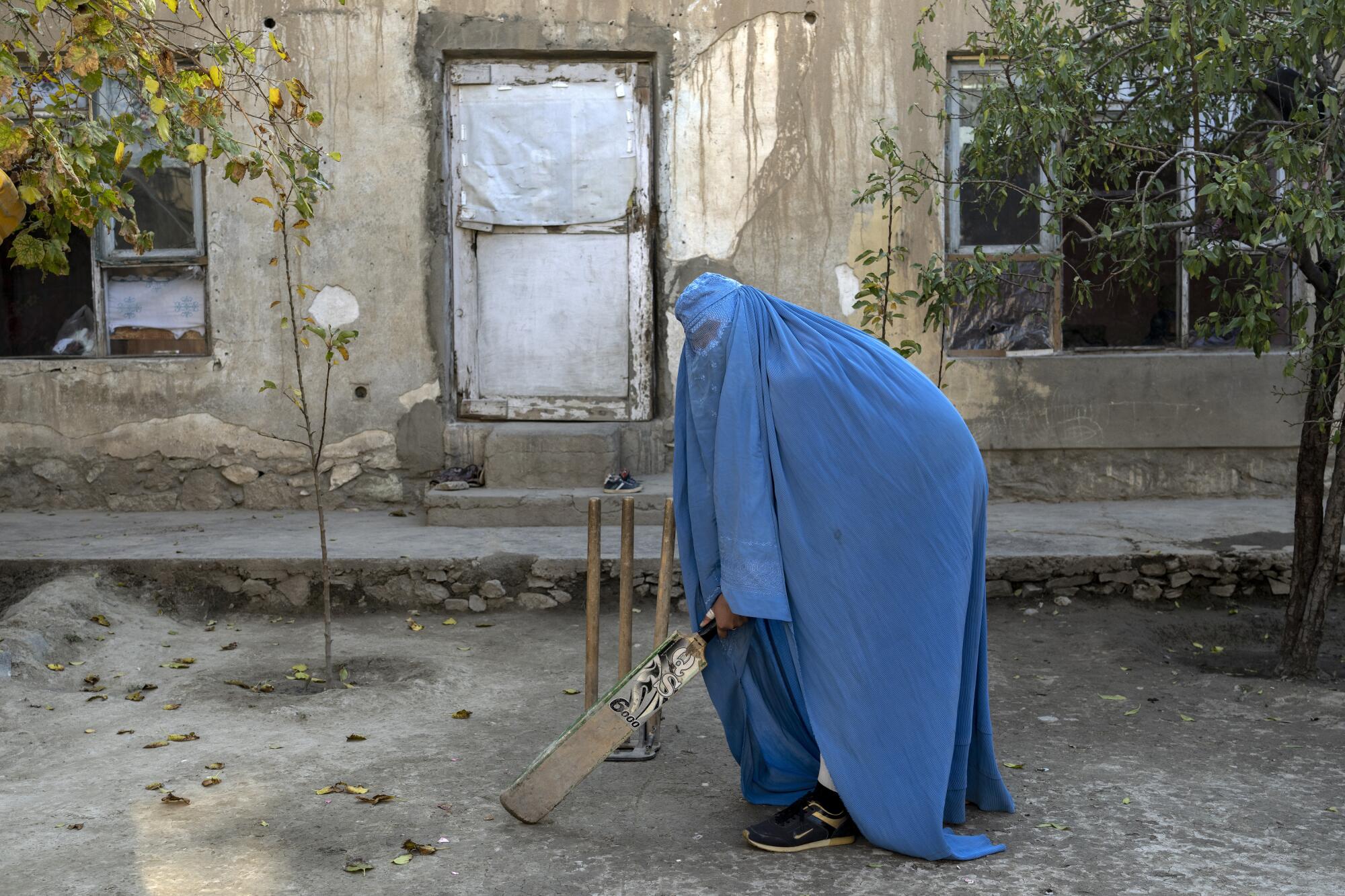 An Afghan woman poses for a photo with her cricket bat