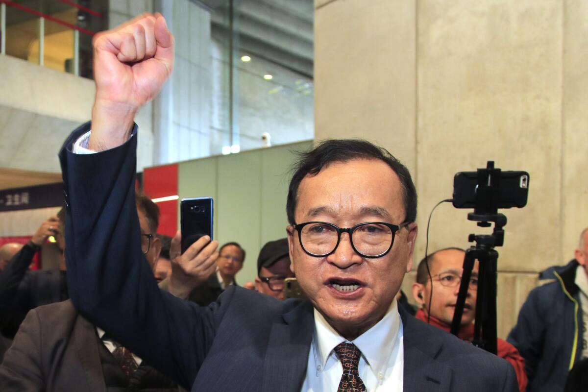 FILE - In this Nov. 7, 2019, file photo, Cambodia's most prominent opposition politician Sam Rainsy clenches his fist as he is attempting to return to Cambodia at Charles de Gaulle airport, north of Paris. Phnom Penh Municipal Court has convicted and sentenced the exiled leader and senior members of the country's banned opposition party to more than 20 years in prison, effectively barring them from ever returning home. The decision taken by the court late Monday, March 1, 2021 was condemned by the head of the Cambodia National Rescue Party , or CNRP, human rights organizations and the United States embassy. The trial was held in absentia as all the party leaders are living abroad. (AP Photo/Michel Euler, File)