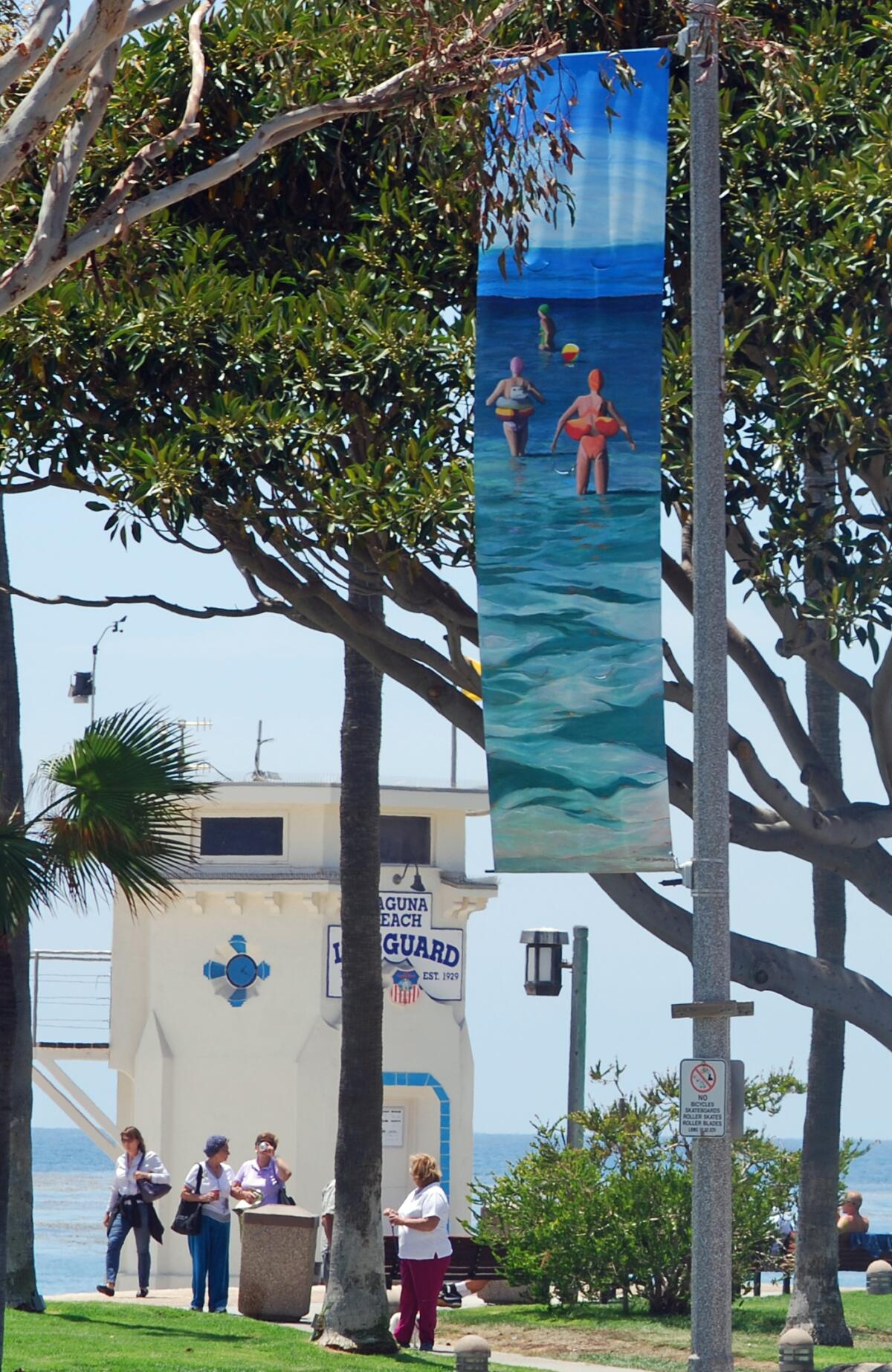 An artistic banner with sunbathers wading into the ocean hangs in Laguna Beach.