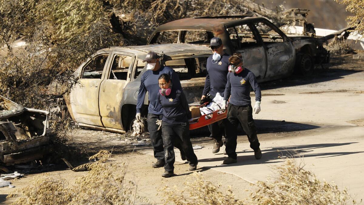 Los Angeles County coroner's workers recover a body at a burned home in the 32000 block of Lobo Canyon Road in Agoura Hills on Wednesday.