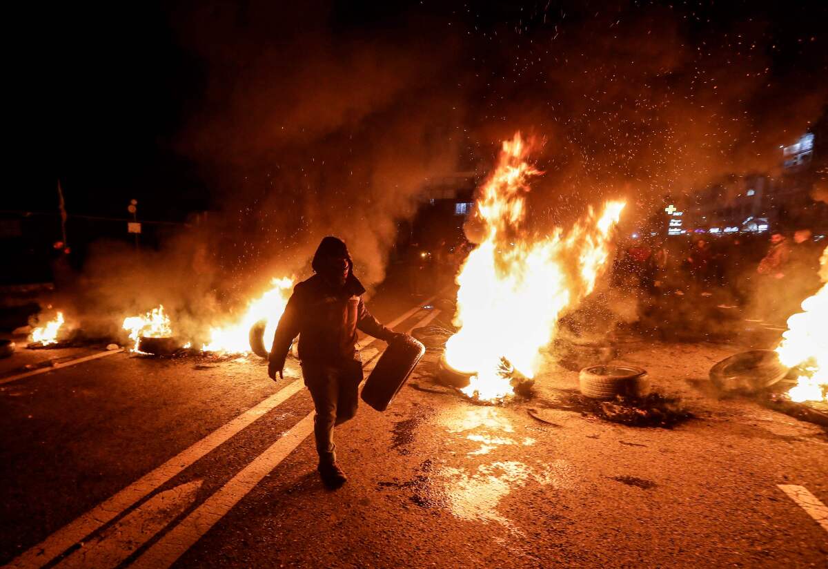 An anti-government protester carries a tyre to be set aflame as a section of the Beirut-Byblos highway is cut off in Byblos on January 21, 2020, as they protest the newly-announced government formed by Prime Minister Hassan Diab.