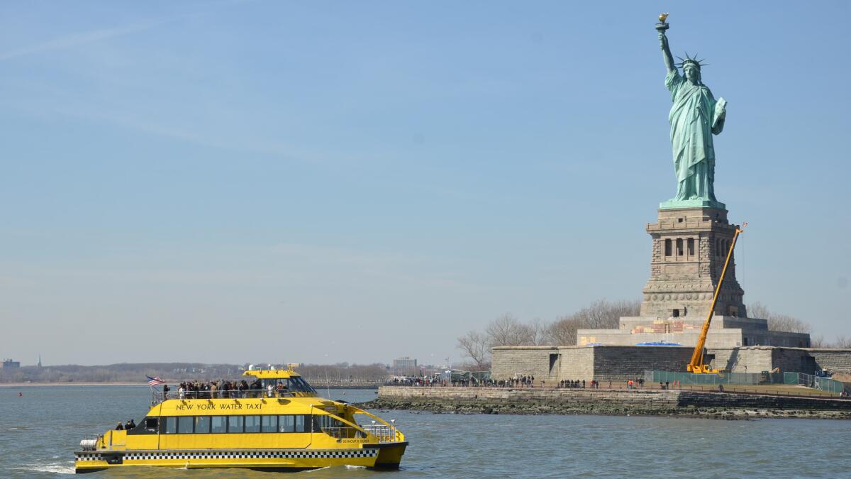 Like a Manhattanite hailing a cab, the Statue of Liberty towers over a New York Water Taxi.