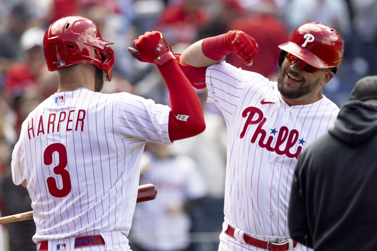 Philadelphia Phillies' Kyle Schwarber celebrates with teammate Bryce Harper (3) after hitting a home run in the first inning of a home opening baseball game against the Oakland Athletics, Friday, April 8, 2022, in Philadelphia. (AP Photo/Laurence Kesterson)