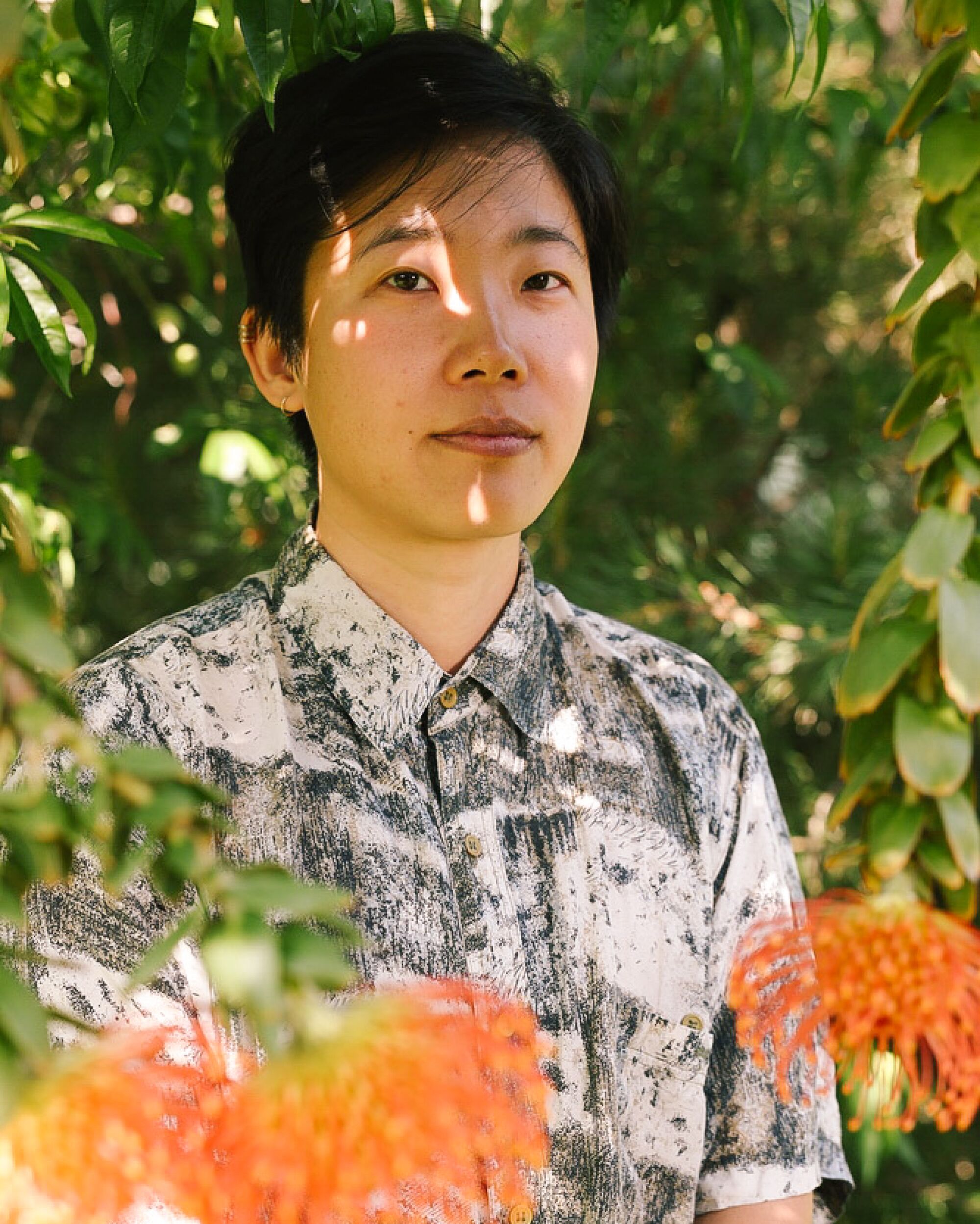 Floral designer Gray Hong poses for a portrait with pincushion protea in their studio at home.