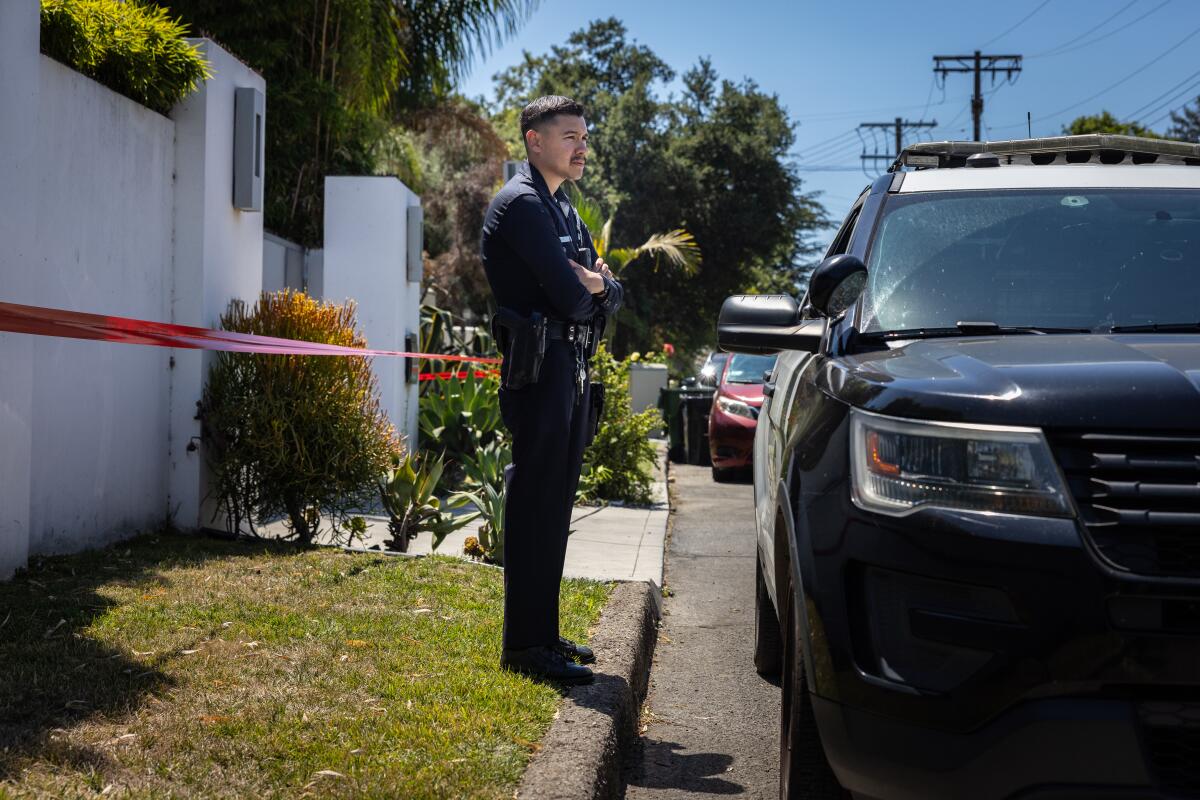 A police man stands in front of a home with white walls
