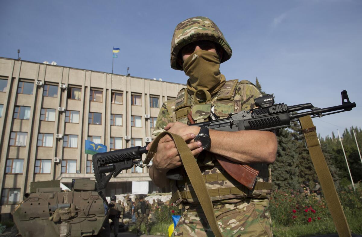 A Ukrainian soldier stands in front of a government building flying the national flag in the eastern city of Slovyansk on Saturday.