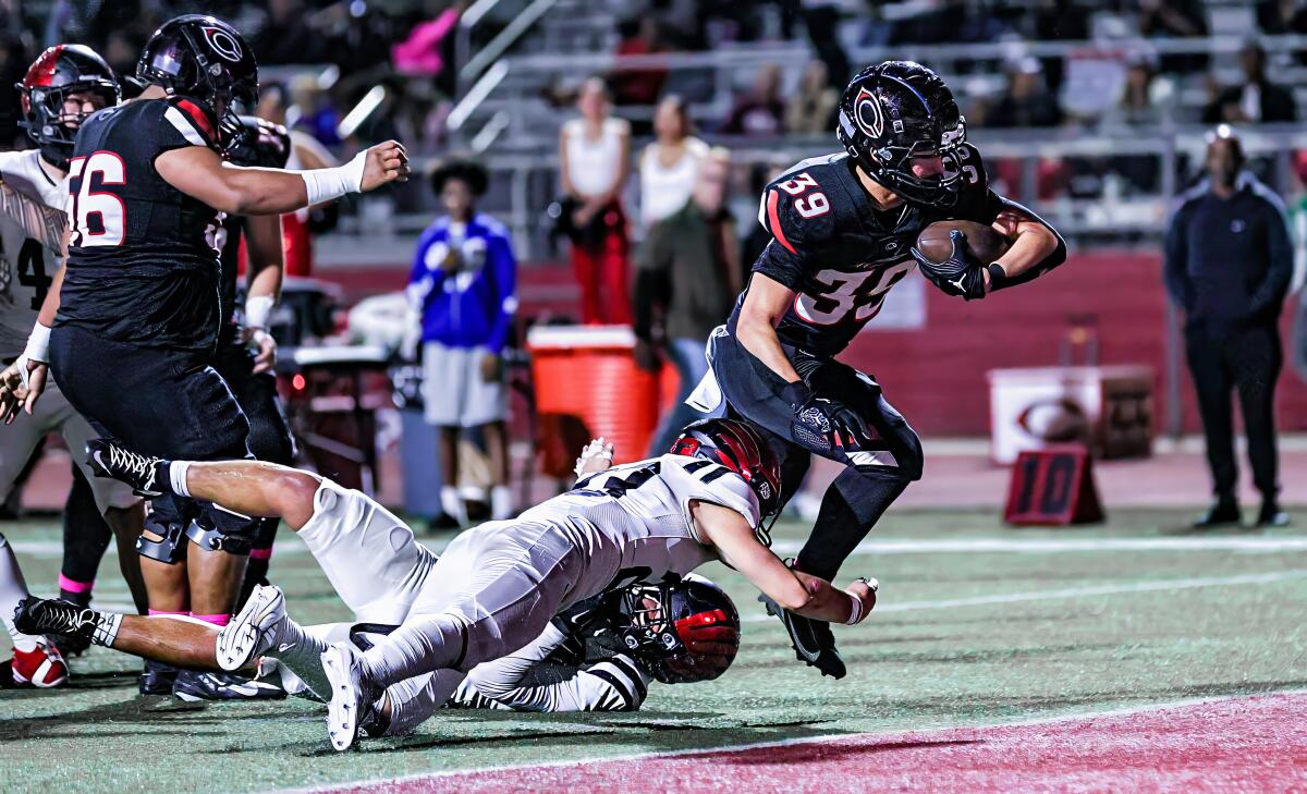 Braylin Drake of Corona Centennial tries to evade two Murrieta Valley defender who try to tackle him low.