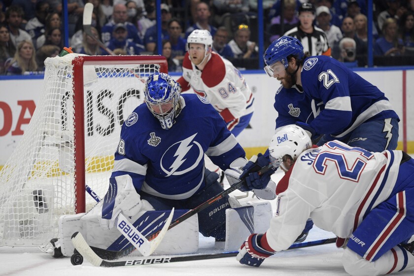 Montreal Canadiens center Eric Staal (21) and Tampa Bay Lightning center Brayden Point (21) reach for the puck next to Lightning goaltender Andrei Vasilevskiy (88) during the first period in Game 5 of the NHL hockey Stanley Cup finals, Wednesday, July 7, 2021, in Tampa, Fla. (AP Photo/Phelan Ebenhack)
