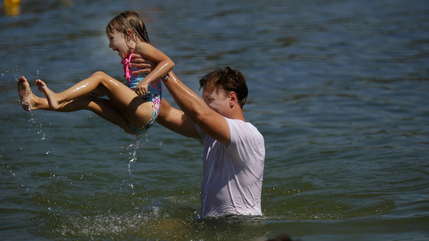 Victor Dudchenko tosses his friend's daughter Julia Bogachuk in the air while they play in the lake at Frank G. Bonelli Regional Park in San Dimas.