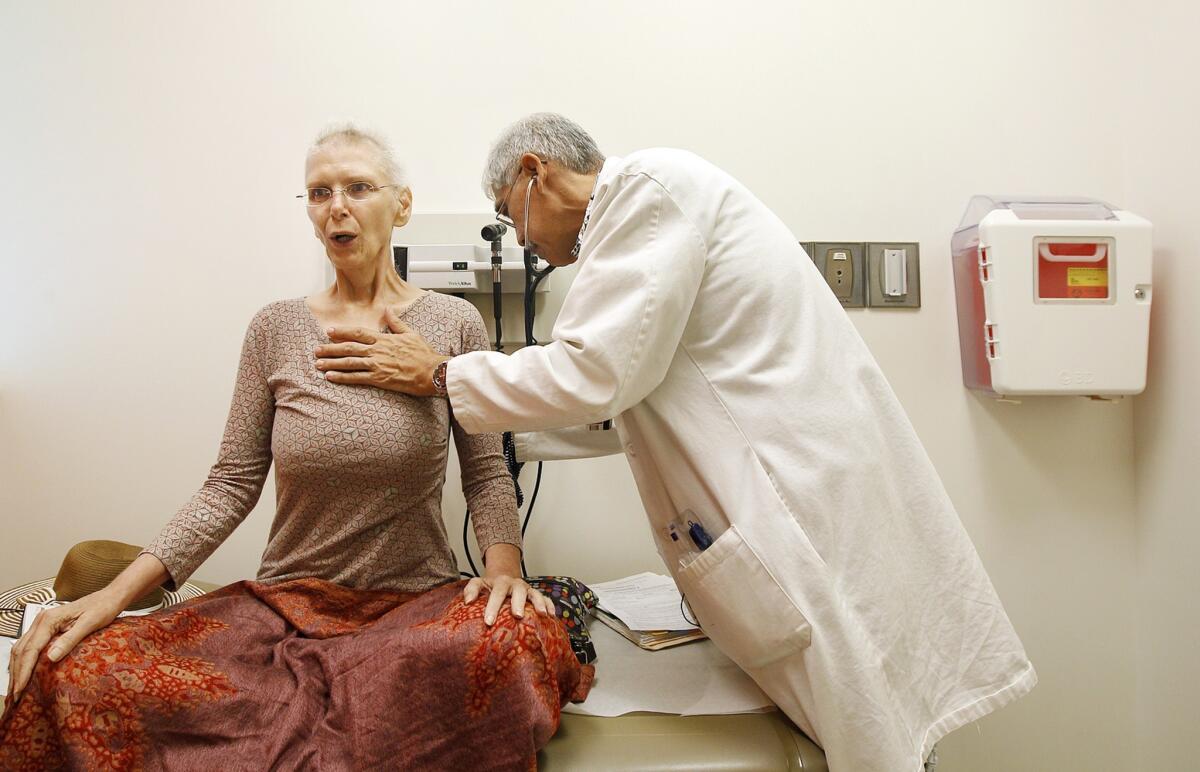 Jul Lynn Parsons of Punalu'u, Hawaii, is examined by Dr. Clayton Chong during a consultation for her ongoing chemotherapy treatment at the Queen's Medical Center cancer center in Honolulu.