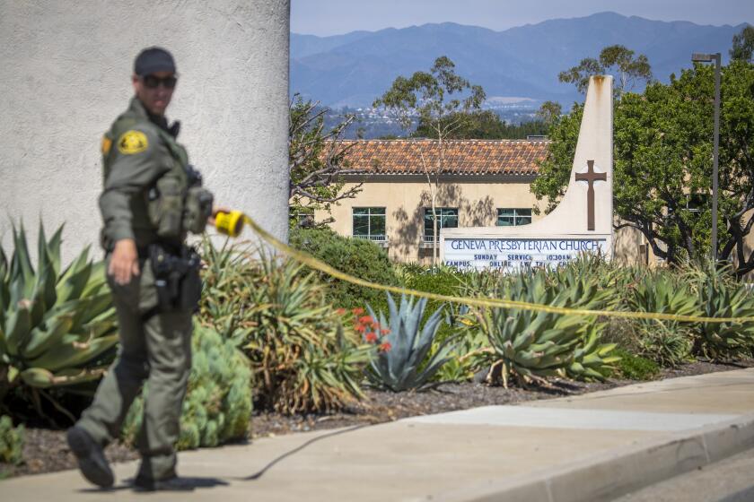 Laguna Woods, CA - May 15: An Orange County Sheriff's Officer places police tape around the exterior of the church after a person opened fire during a church service attended by a Taiwanese congregation, killing one person and critically injuring four others at Geneva Presbyterian Church in Laguna Woods Sunday, May 15, 2022. Authorities are interviewing more than 30 people who were inside the church at the time. The victims were described as mostly Asian and mostly of Taiwanese descent, authorities said. A law enforcement source said officials believe the suspect was a 68-year-old Asian man who is originally from Las Vegas. The source said after the suspect opened fire he was "subdued" by parishioners. No other details were available. (Allen J. Schaben / Los Angeles Times)