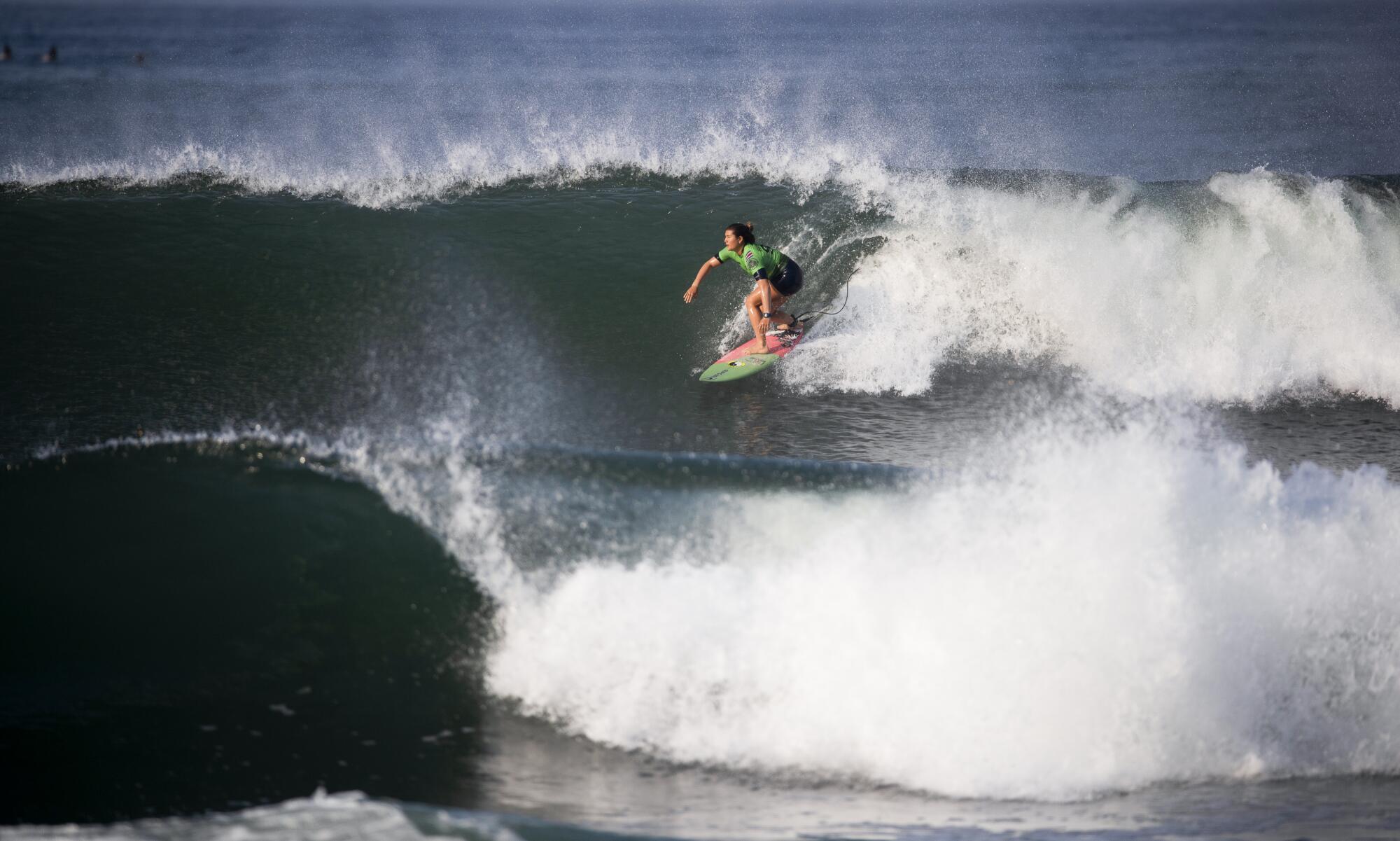 Brisa Hennessy is illuminated by the sunrise while riding nicely shaped waves in the first match against Stephanie Gilmore.