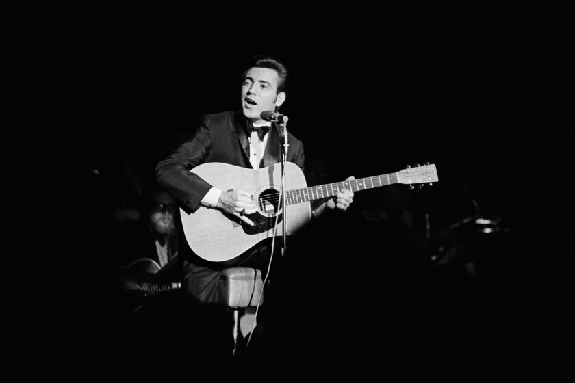 Singer  Jimmie Rodgers, with guitar, performing on stage.