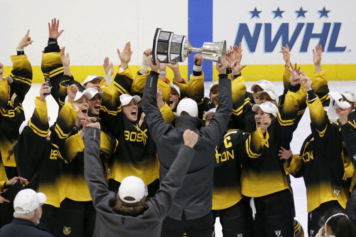 FILE - Boston Pride players cheer as coach Paul Mara hoists the NWHL Isobel Cup trophy after the team's win over the Minnesota Whitecaps in the championship hockey game in Boston, Saturday, March 27, 2021. With a new name and an influx of private ownership, the Premier Hockey Federation -- formerly the National Women's Hockey League -- prepares to open its seventh season this weekend, and first with a full slate of games in two years. (AP Photo/Mary Schwalm, File)
