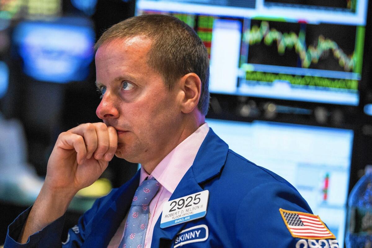A trader works on the floor of the New York Stock Exchange on Monday. After a volatile day of trading the Dow Jones industrial average closed down 114.98 points, or 0.7%, to 16,528.03.