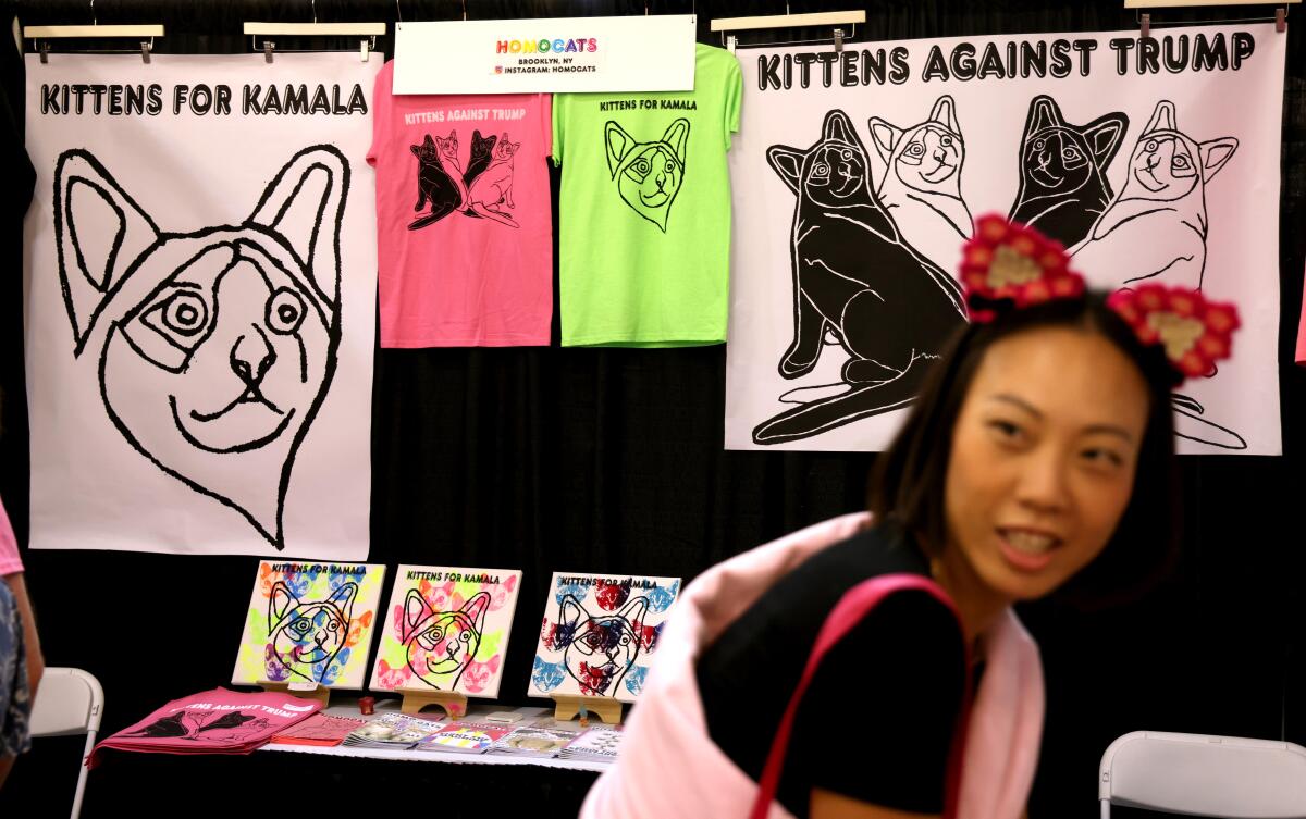 A woman wearing cat ears and standing in front of T-shirts and other merchandise.