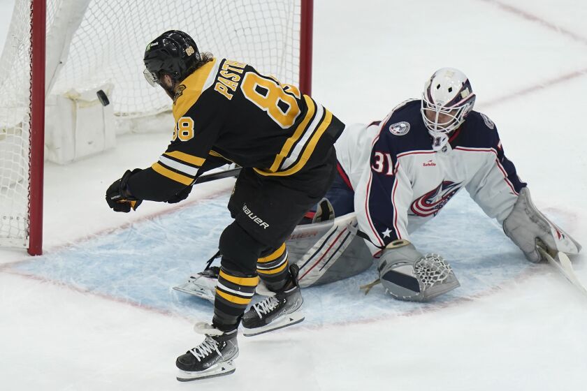 Boston Bruins right wing David Pastrnak (88) scores the winning goal as Columbus Blue Jackets goaltender Michael Hutchinson (31) tries to defend in overtime of an NHL hockey game, Thursday, March 30, 2023, in Boston. (AP Photo/Steven Senne)