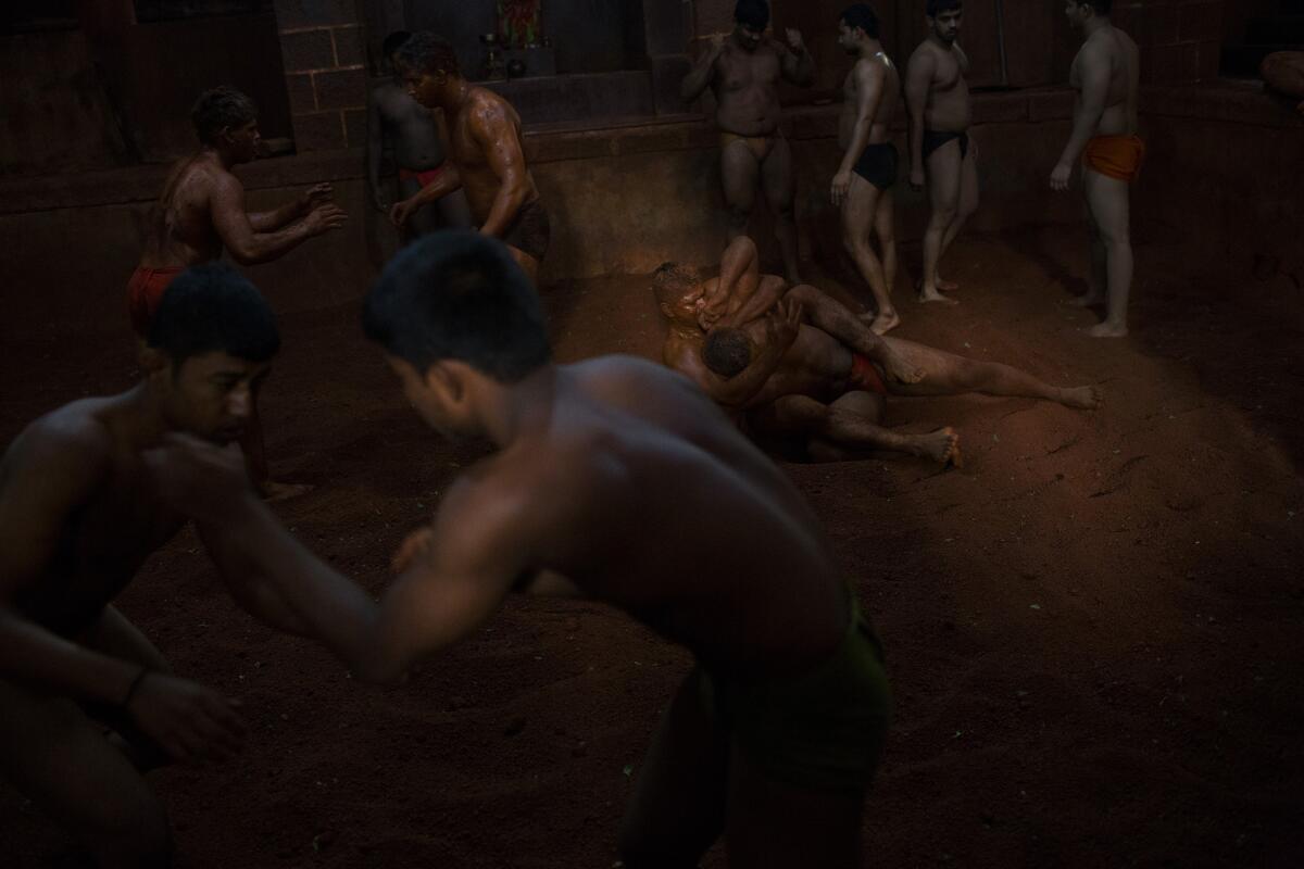 A kushti practioner prepares the floor, which is made from clay -- a mixture of dirt, yogurt, clarified butter and turmeric powder.