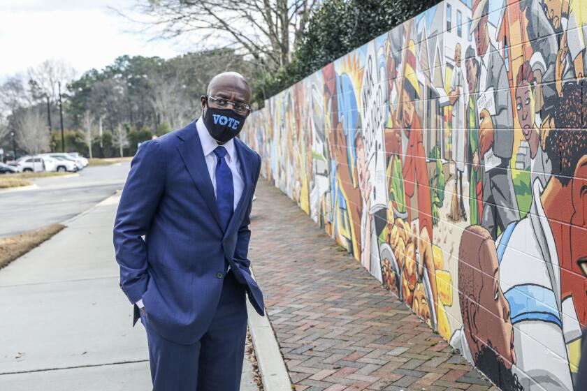 Georgia Senatorial candidate Reverend Raphael Warnock looks at a mural dedicated to Elizabeth Porter who was a local Civil Rights icon, at a canvassing event on January 5, 2021 in Marietta, Georgia. - Voters headed to the polls for runoff elections in the southern state of Georgia on Tuesday that will determine control of the US Senate for the first years of Joe Biden's presidency. "It's the most important election in my lifetime," said Robert Lowe, a 74-year-old retired improv comedian, after casting his ballot for the Democrats on the ticket, Jon Ossoff and the Reverend Raphael Warnock. (Photo by SANDY HUFFAKER / AFP) (Photo by SANDY HUFFAKER/AFP via Getty Images)