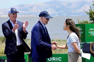 President Joe Biden, center, shakes hands with Chiena Ty, right, while Gavin Newsom applauds at left. 