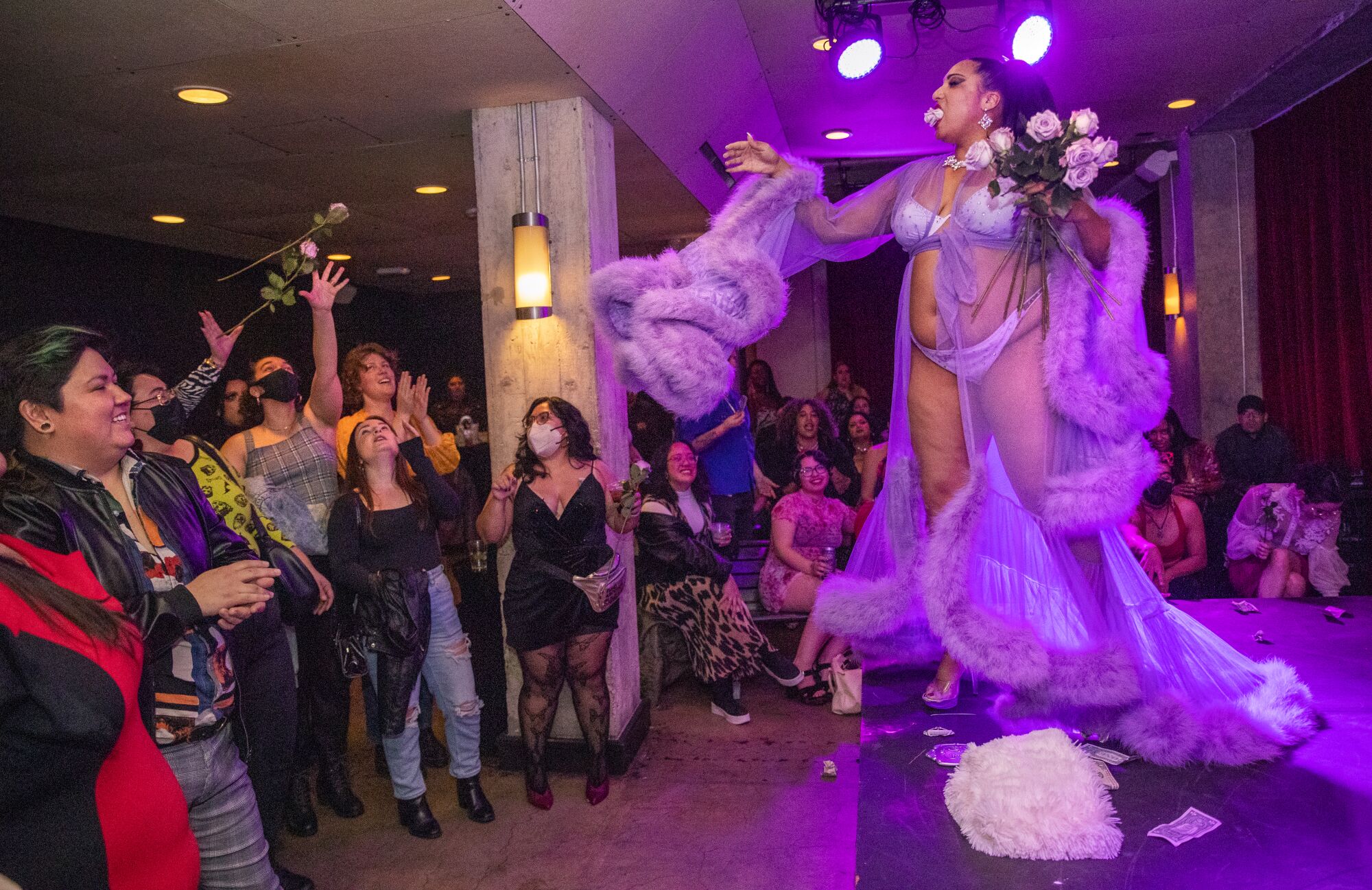 A burlesque performer dances in a long robe.