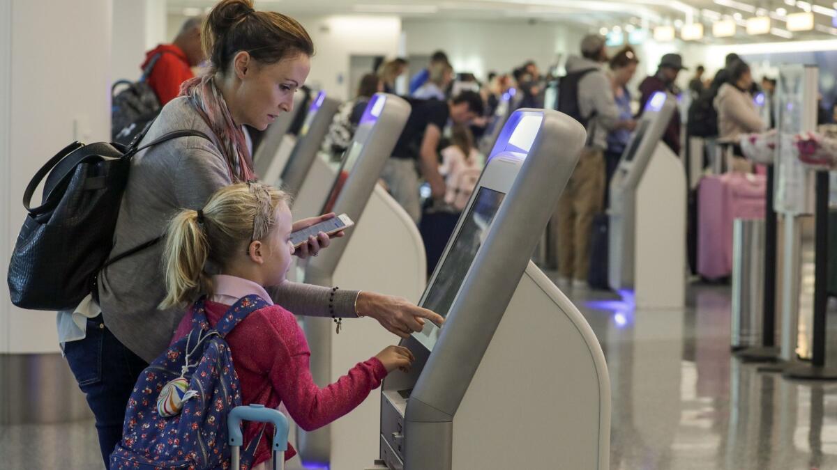 Katy Von Treskow and her daughter use a check-in kiosk last year at Los Angeles International Airport. More airlines are adding such stations to help reduce wait times.