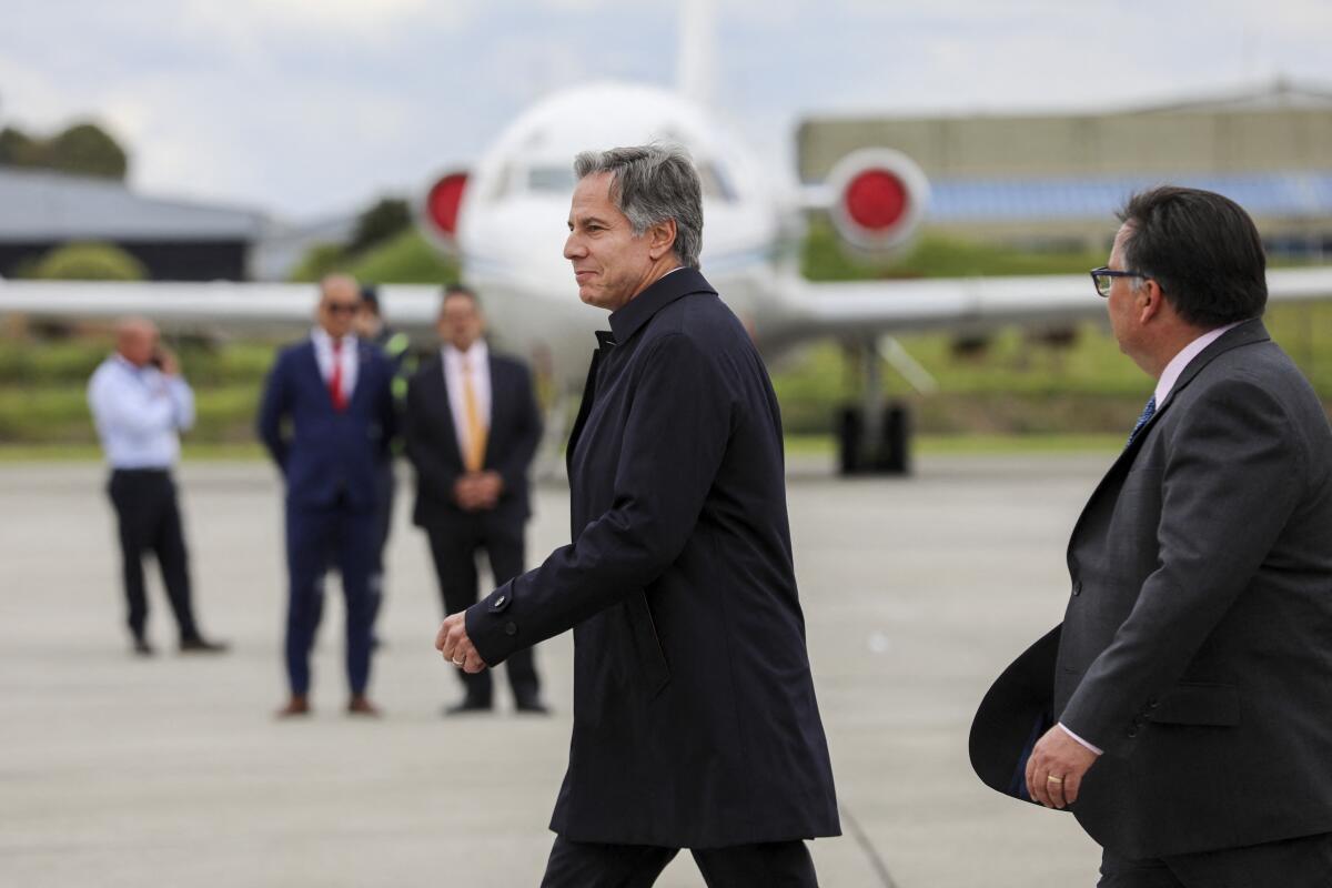 Secretary of State Antony Blinken walks on an airport tarmac near other people