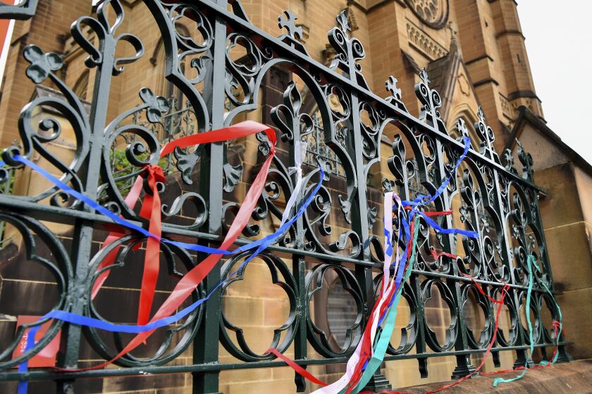 Ribbons are tied onto a fence as a protest at St Mary's Cathedral, in Sydney, Tuesday, Jan. 31, 2023. Police plan to ask a judge to ban gay rights protesters from demonstrating outside St. Mary's Cathedral during Australian Cardinal George Pell's Sydney funeral Wednesday. (Bianca De Marchi/AAP Image via AP)