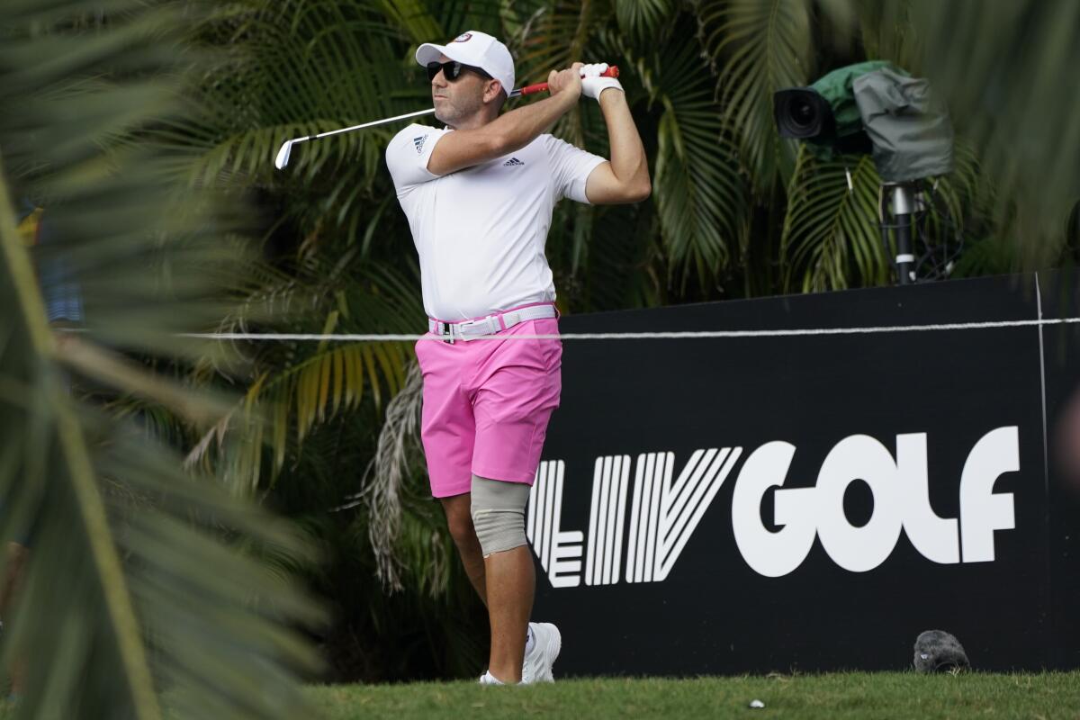Sergio Garcia hits a ball in front of a LIV Golf sign.
