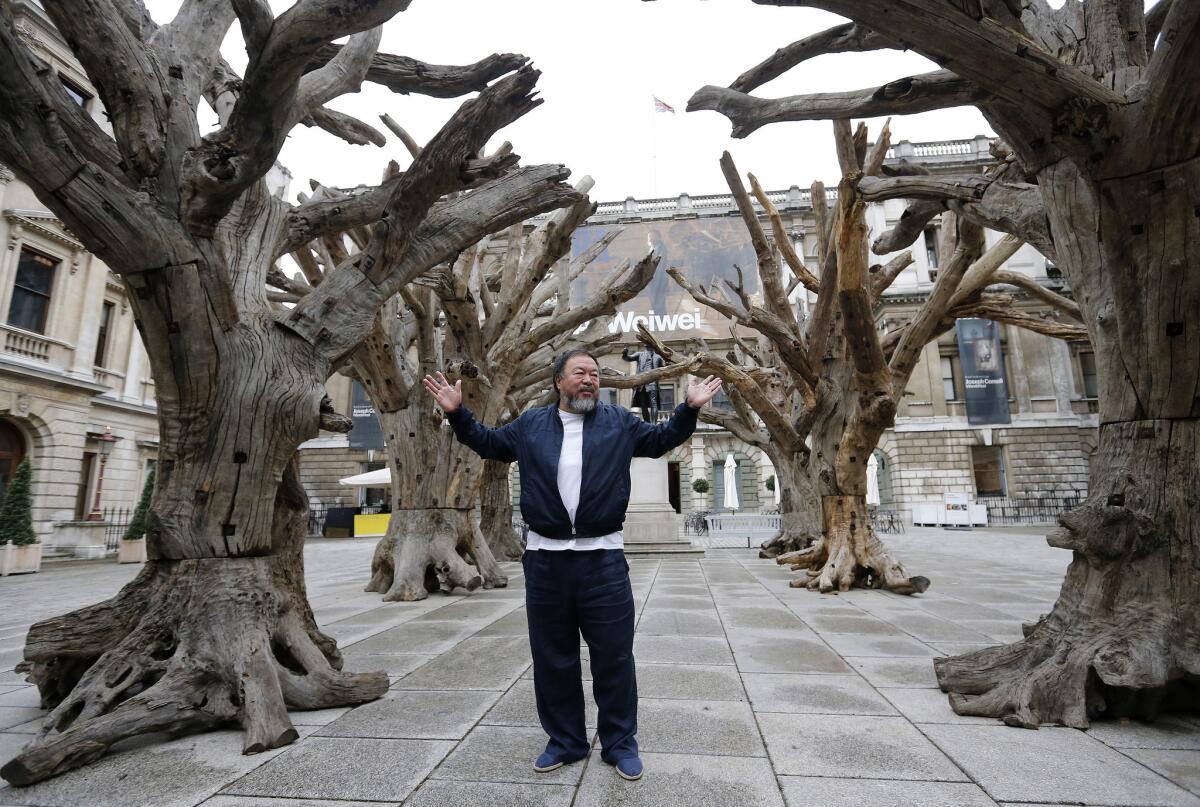 Chinese artist Ai Weiwei poses for photographers with one of his pieces at his exhibition at the Royal Academy of Arts in London on Sept. 15.