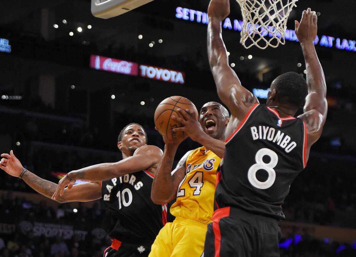 Lakers guard Kobe Bryant tries to score inside against Raptors guard DeMar DeRozan (10) and center Bismack Biyombo in the second half.